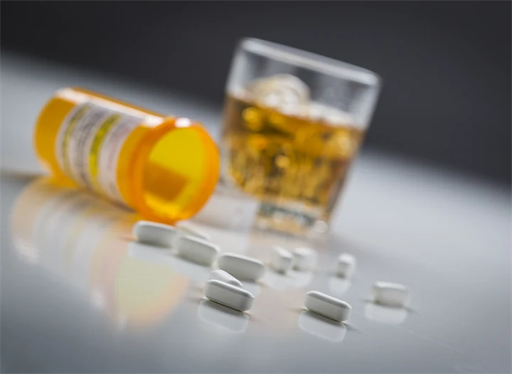 Närbild på tabletter och glas med alkohol.