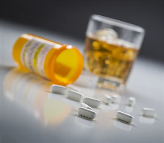 Närbild på tabletter och glas med alkohol.